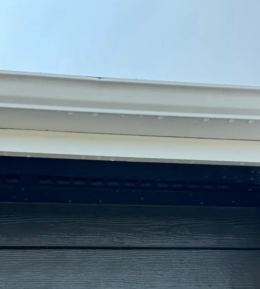 Bright white fascia and gutter line above dark lap siding after cleaning